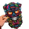 Smell Crusher skull mask with the colourful graffiti skull artwork, held in hand